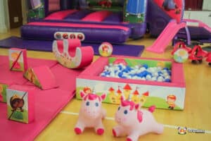 A colorful princess-themed play area with a bouncy castle, slide, and assorted toys for children's entertainment.