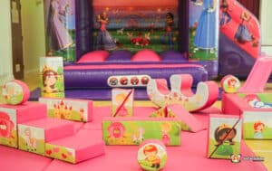 A delightful play area with a bouncy castle, slide, and toys, designed as part of a princess soft play package for kids.