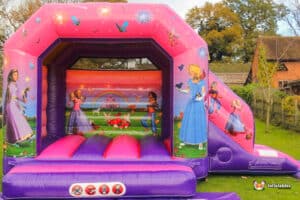 A colorful bouncy castle featuring princess graphics, set up for children's play and entertainment at an outdoor event.