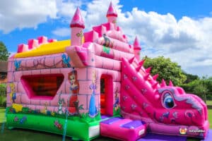 A vibrant pink castle with a slide, with princess and dragon art work.