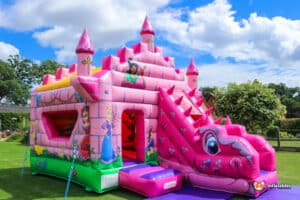 A fairytale-themed pink castle with a dragon slide, featuring a princess on top, inviting children to play and explore.