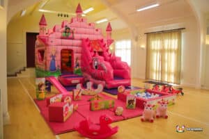 A pink fairytale-themed bouncy castle with a slide and a soft play area designed for children.