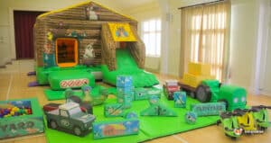 A play area featuring a farm playbarn, inflatable toys, and a slide, designed for children's outdoor fun and activities.