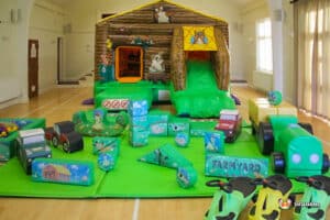 Outdoor play area with a farm playbarn, colorful inflatable toys, and a slide, providing a fun space for children.