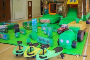 A vibrant play area showcasing a farm playbarn, inflatable toys, and a slide, perfect for children's playtime adventures.