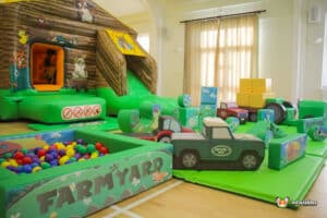 Play area with a farm playbarn, inflatable toys, and a slide, creating an engaging environment for children's outdoor play.