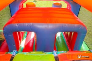 Colorful inflatable play structure with orange, blue, and green sections, designed for children’s bouncing and climbing activities.
