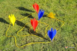Colorful yard game setup with red, yellow, and blue stakes arranged in a playful design on green grass.