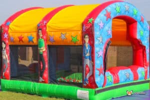 A colourful inflatable gigantic ball pool featuring bright star patterns and cartoon characters, set against a clear blue sky.