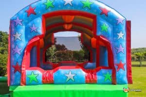 A colourful inflatable gigantic ball pool featuring bright stars and a vibrant archway in an outdoor setting, perfect for kids' parties.