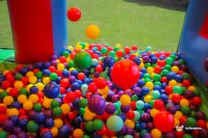 A vibrant ball pit filled with colorful plastic balls in red, yellow, green, blue, and purple, under a playful inflatable structure.