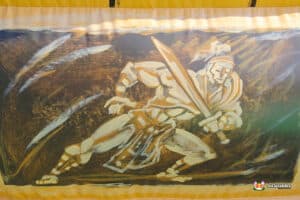 A large mural of a warrior, prominently displayed on a wall, featuring dynamic poses and rich artistic details.