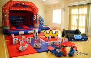 A room featuring a Spider-Man bouncy castle surrounded by various colorful toys scattered on the floor.