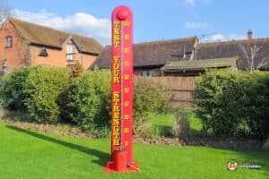 A large red high striker, which looks like a thermometer, at a funfair attraction.