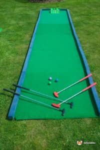 A miniature golf course featuring a green mat and a golf ball, highlighting a "Hole in 1" achievement.