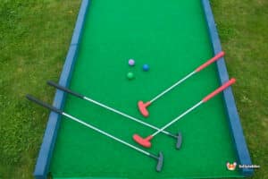 A close-up of a miniature golf course with a green mat and a ball, celebrating a successful "Hole in 1."
