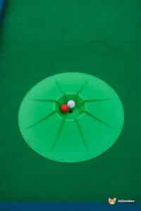 A miniature golf setup with a green mat and a ball.