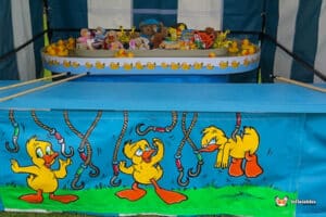 A colourful carnival hoo a duck side stall featuring animated ducks, plush toys, and yellow rubber ducks, inviting fun and excitement.