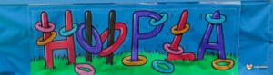 Colourful "HOOPLA" banner featuring vibrant letters and playful rings on a grassy background, promoting a fun outdoor game.