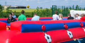 A group of people enjoying a lively game of Human Football, focused on the action at the foosball table.
