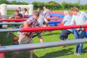 A lively scene of people playing Human Table Football, showcasing teamwork and enthusiasm around the foosball table.