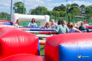 A group of players intensely focused on a Football, with colourful foosball figures in action.