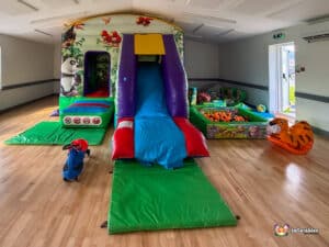 Children's play area showcasing a slide, jungle gym, tiger rocker, and soft play features for active play and exploration.