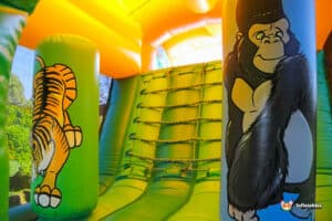 Interior of a colorful inflatable slide featuring a tiger and a gorilla, surrounded by bright yellow and green walls.