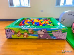 A vibrant jungle soft play area showcasing a large ball pit overflowing with colorful balls for kids to play in.