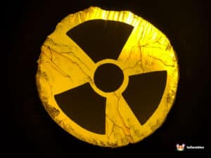 Glowing yellow radioactive symbol against a dark background, resembling a cracked stone texture.