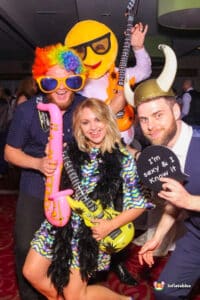 Friends dressed in various costumes smiling and posing for a picture by a Magic Photo Mirror.