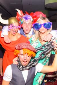 A group of people in colourful costumes posing together for a photo in front of a Magic Mirror.
