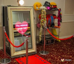 A Magic Photo Mirror displayed on a red carpet, surrounded by a red rope for an elegant photo experience.