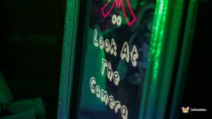 Neon sign reading "Look at the Camera" with a vibrant glow, part of the Magic Photo Mirror experience.