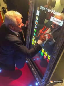 Kevin Keegan in a suit gazes into a mirror, featuring the Magic Photo Mirror.