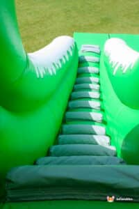 Green inflatable slide with accessible steps, perfect for sliding down.