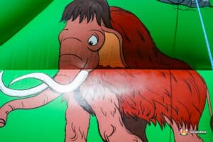 Cartoon mammoth happily lounging on a green and red inflatable, showcasing a fun and whimsical design.