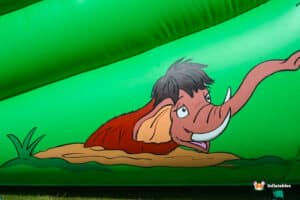 A playful cartoon mammoth on a vibrant green and red inflatable, exuding a sense of joy and adventure.