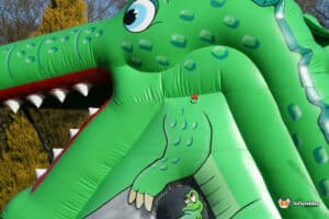 A vibrant inflatable crocodile slide showcasing a big mouth, providing fun and excitement for children at play.