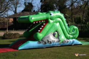 A colorful inflatable crocodile slide in a sunny garden, perfect for kids to enjoy a fun day of sliding and laughter.