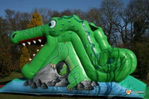 A whimsical inflatable crocodile slide in a green garden, offering a fun and adventurous playtime for kids.