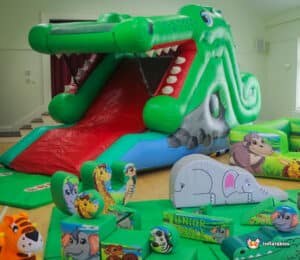 Jungle-themed inflatable play area showcasing various animals, highlighted by a crocodile slide and soft play equipment.