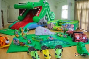 Colorful inflatable jungle-themed play area with animal figures, featuring a crocodile slide and soft play shapes for children.