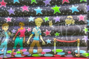 Colorful cartoon characters on a bouncy castle backdrop with stars and a VIP area, adding fun and excitement to the scene.