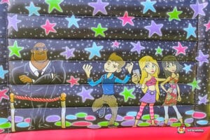 Colorful inflatable wall featuring cartoon characters: a man in a suit, a boy dancing, and two girls posing, surrounded by stars.