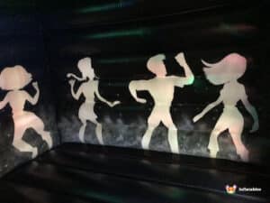 Silhouettes of four dancers in a colourful, inflatable bouncy castle, creating a fun and lively atmosphere.