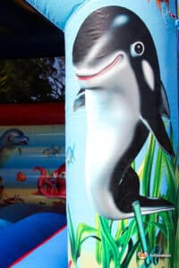 A vibrant inflatable pillar featuring a smiling dolphin among ocean plants, with a colourful underwater scene in the background.