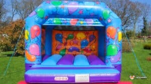 . A colorful bouncy castle decorated with balloons and festive decorations, perfect for a fun outdoor celebration.