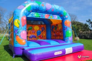 A vibrant balloon-themed bouncy castle adorned with colorful decorations, inviting children to jump and play.