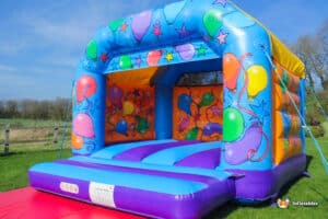 . A lively inflatable bouncy castle decorated with balloons, providing a playful space for children to enjoy.
